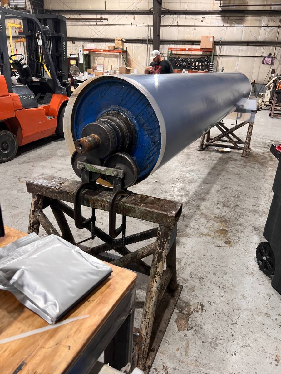 Fluoron technician installing a heat-shrink fluoropolymer roll cover on an industrial roller.